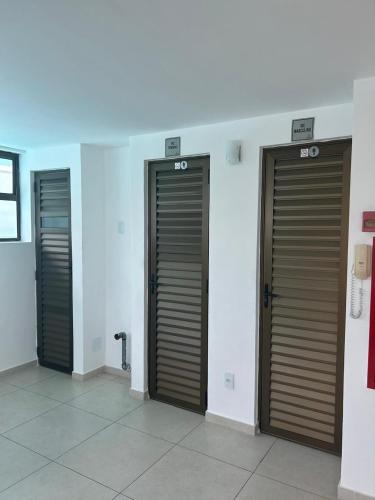 three bathroom stalls with brown doors in a room at Flat Boa Viagem -500 m praia - Golden Style in Recife