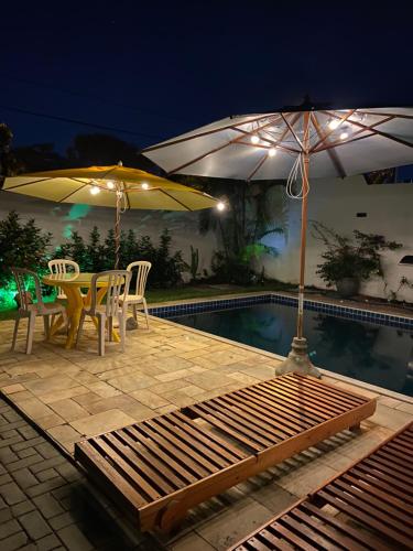 a patio with a table and an umbrella and a pool at Casa bela in Lauro de Freitas