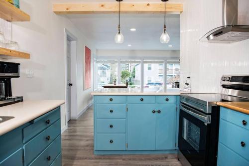 a blue kitchen with white walls and wooden floors at Seaside Retreat Hot Tub Steps to Beach Slps 6 in Seaside