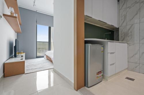 a kitchen with a refrigerator and a bedroom at Stylish Studio Near Dubai Academic City in Dubai