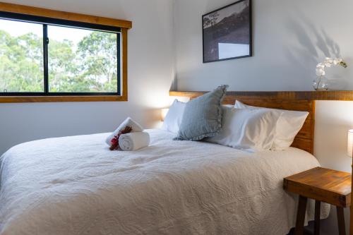 a bedroom with a white bed with a teddy bear on it at Mount Mee Country Lodge in Mount Mee