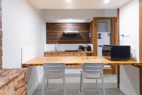 a kitchen with a wooden counter and white chairs at Mount Mee Country Lodge in Mount Mee