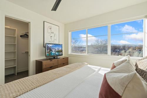 a bedroom with a bed and a tv and a window at Mountain View Home with King Beds and Rooftop Deck in Fort Collins