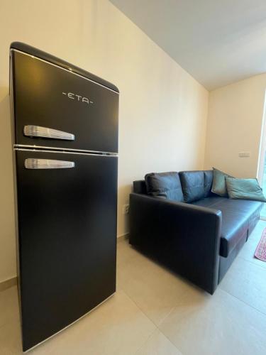 a black refrigerator in a living room with a couch at Apartmán Bellevue in Boskovice