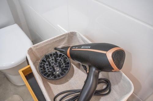 a hair dryer sitting in a box next to a toilet at ApArtStudio in Oliveira de Frades