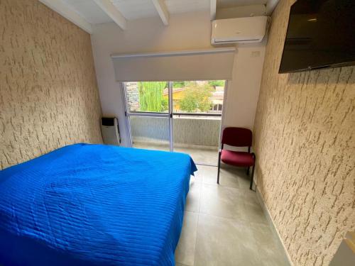 ein Schlafzimmer mit einem blauen Bett und einem roten Stuhl in der Unterkunft Magdalena in Santa Rosa de Calamuchita