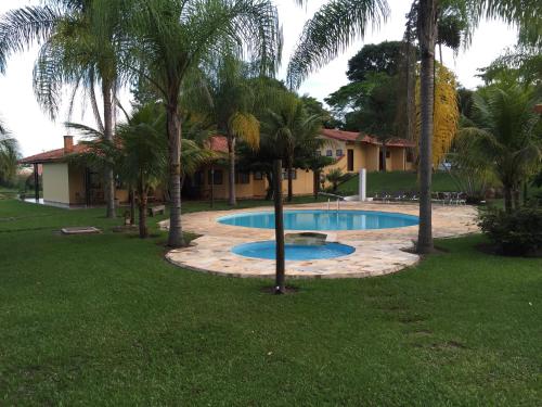 a swimming pool in a yard with palm trees at Pousada Sarapui in Sarapuí