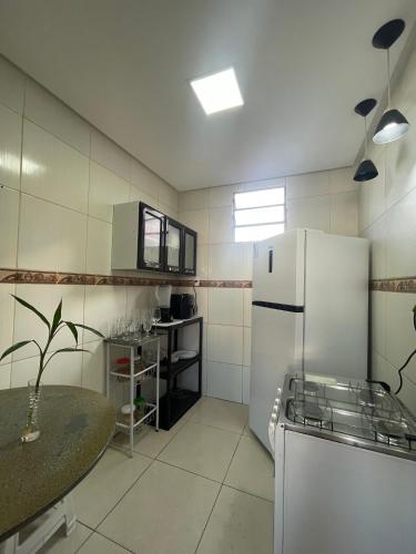 Una cocina con un refrigerador blanco y una mesa. en Quarto Eliote, en Aracaju