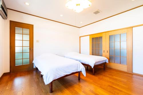 two beds in a room with wooden floors at SAKURA Ideal Base for Yoshino & Koyasan in Gojō