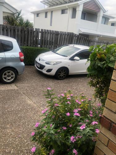 two cars parked in a driveway next to a fence at Private room in Gold Coast