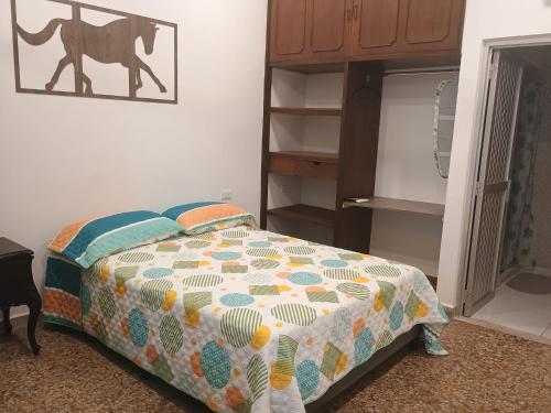 a bedroom with a bed with a quilt on it at HOTEL GANADERO in La Dorada