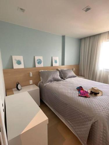 a bedroom with a bed and a table with a hat at Paraíso Azul em Ponta Negra, Natal RN in Natal