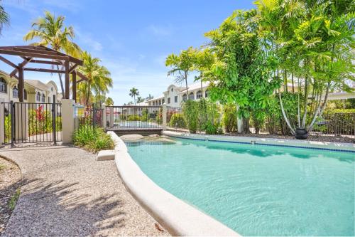a swimming pool with a fence and trees at Dasheri at Mango Lagoon Resort in Palm Cove