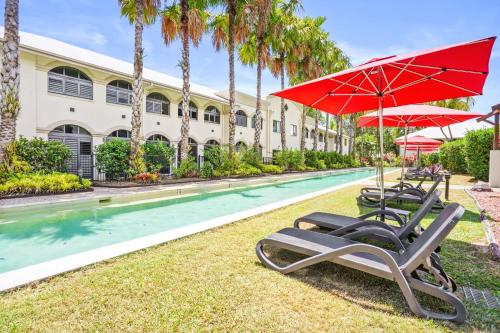a group of chairs and umbrellas next to a pool at Dasheri at Mango Lagoon Resort in Palm Cove