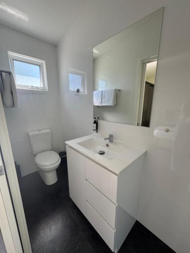 a white bathroom with a toilet and a sink at Port Arthur Villas in Port Arthur