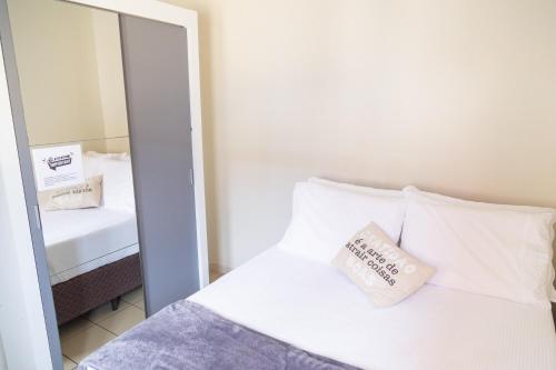 a bedroom with a white bed and a mirror at Conforto em local privilegiado in Itajaí