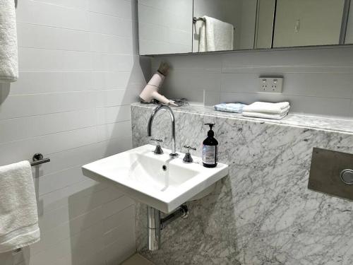 a bathroom with a white sink and a mirror at Modern Loft Retreat in Barton Canberra ACT near Parliament House in Barton