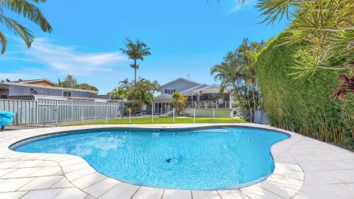 a swimming pool in a yard with palm trees at 'Waterfront Oasis' by HolidayCo in Chittaway Point