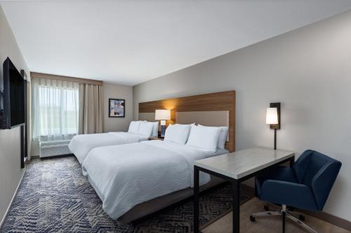 a hotel room with two beds and a desk and a television at Candlewood Suites McPherson by IHG in McPherson