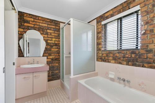 a bathroom with a white tub and a sink and a mirror at Banksia Beach Views! in Banksia Beach