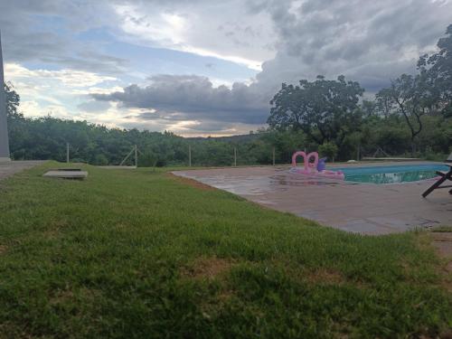 a swimming pool with pink plastic chairs in a yard at Estância da Mata, Brasil in Lapinha
