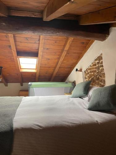 a large bed in a room with wooden ceilings at El Balcón de Urbiés in Mieres