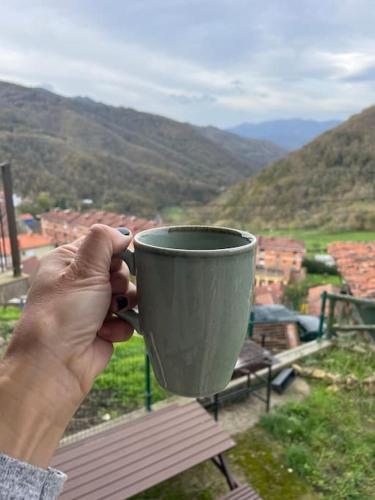a person holding a cup of coffee on a table at El Balcón de Urbiés in Mieres