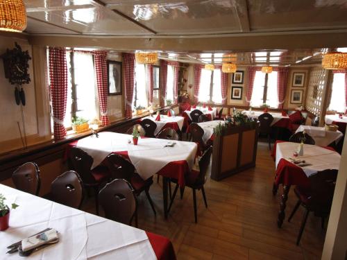 a restaurant with white tables and chairs and windows at Schwarzwaldgasthof Hotel Schwanen in Schonach