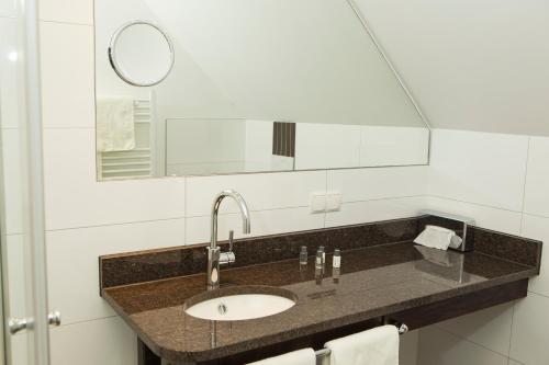 a bathroom with a sink and a mirror at Hotel Niedersächsischer Hof in Bad Bentheim