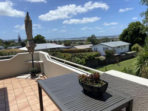 a patio with a table and an umbrella on a balcony at Close motorway, free breakfast, Fabulous views, selfcontained in Auckland