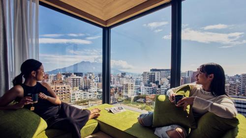 鹿児島市にあるFAV LUX 鹿児島天文館の市街の景色を望む部屋に座る女性2名