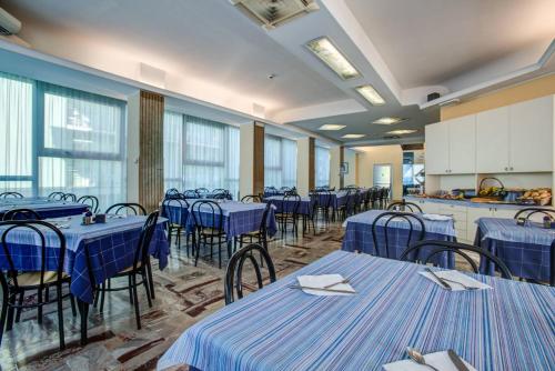 a room with blue tables and chairs and windows at Hotel San Paolo in Rimini