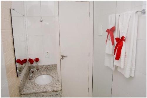 a bathroom with a sink and a shower with red bows at Hotel QualitySul in Teixeira de Freitas