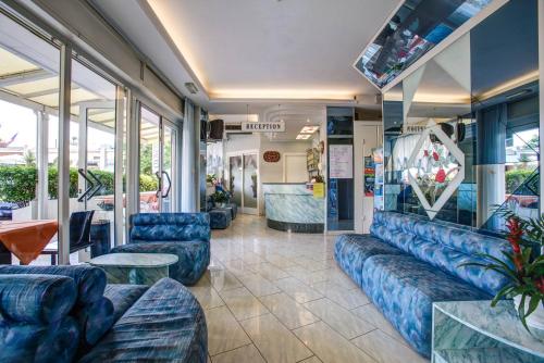 a waiting room with blue couches and tables and windows at Hotel San Paolo in Rimini