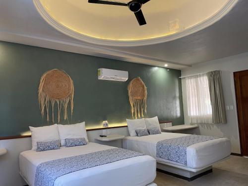 a bedroom with two beds and a ceiling at Hotel Circulo Bacalar in Bacalar