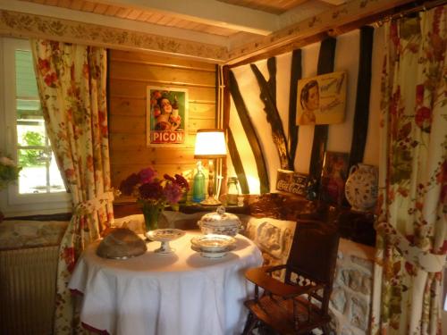 a small table in a room with a lamp and flowers at Chambre d'hôtes Au Fil De L'eau in Jumièges