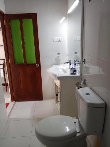 a bathroom with a toilet and a sink with a green door at Seethani Beach Hotel in Hikkaduwa