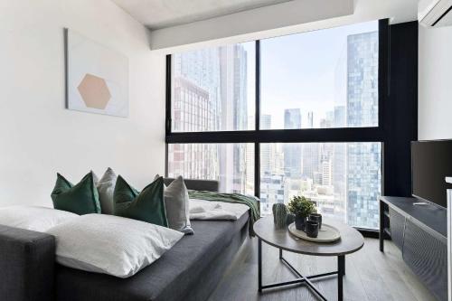 a living room with a couch and a large window at Stylish 2BR Apartment with Panoramic City Views in Melbourne