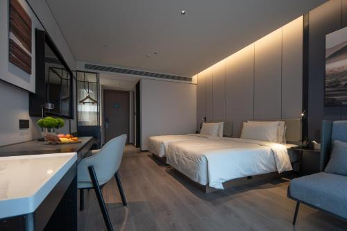 a hotel room with a bed and a table and chairs at Atour Hotel Zigong Huashang International City Summit Park in Zigong