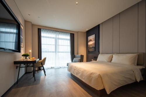 a bedroom with a large bed and a desk and a table at Atour Hotel Zigong Huashang International City Summit Park in Zigong