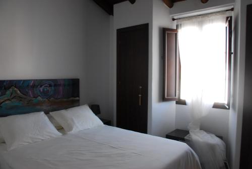1 dormitorio con cama blanca y ventana en Casa Millán, en Puerto Moral