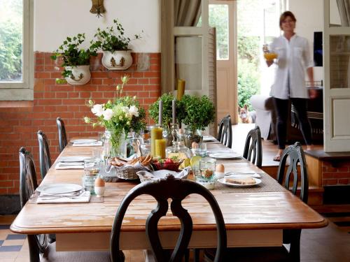 a long wooden table with food and a woman in the background at Hotel Station Amstelveen in Amstelveen