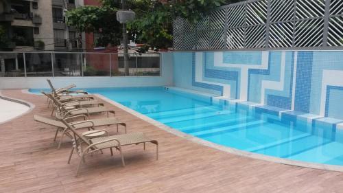 einen großen Pool mit Stühlen und einem blauen Pool in der Unterkunft Apartamento Coração do Carnaval in Salvador