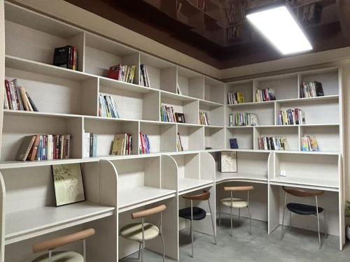 a library with white shelves with chairs and books at Lane Wisdom Garden Hotel - Lijiang Ancient City Zhongyi Market in Lijiang