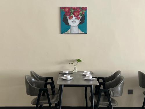 a table with chairs and a painting of a woman at Lane Wisdom Garden Hotel - Lijiang Ancient City Zhongyi Market in Lijiang
