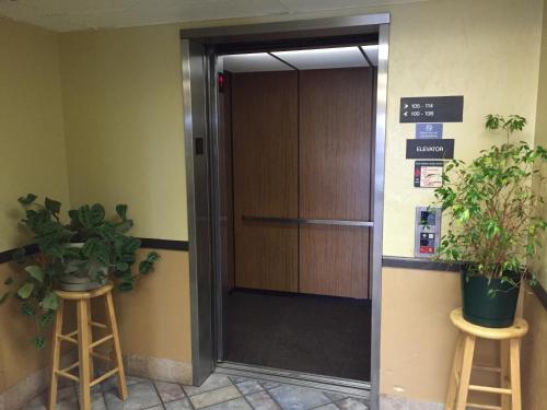 an elevator in an office with two potted plants at Motel 6-Wilsonville, OR - Portland in Wilsonville