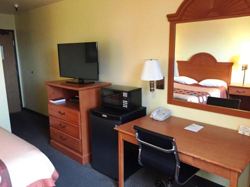 a hotel room with a desk with a television and a bedroom at Motel 6-Wilsonville, OR - Portland in Wilsonville
