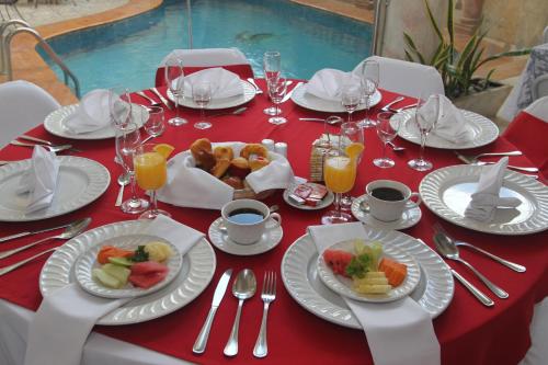 a red table with plates of food on it at Hotel Residencial in Mérida