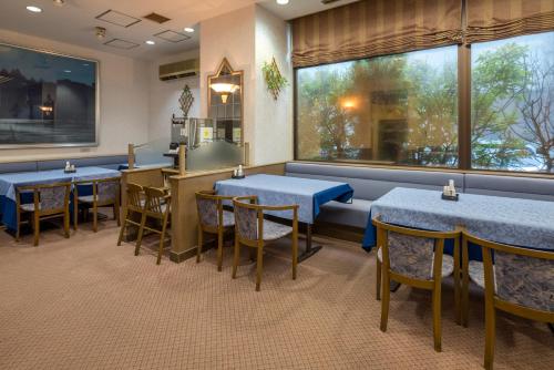 a restaurant with blue tables and chairs and a window at Taira View Hotel in Iwaki