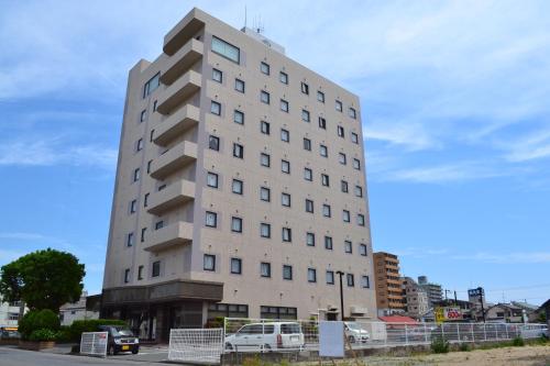 a tall white building with cars parked in front of it at Taira View Hotel in Iwaki